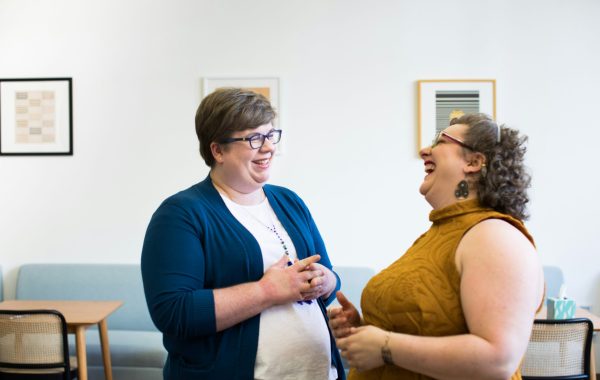Two women standing and looking at each other whilst laughing