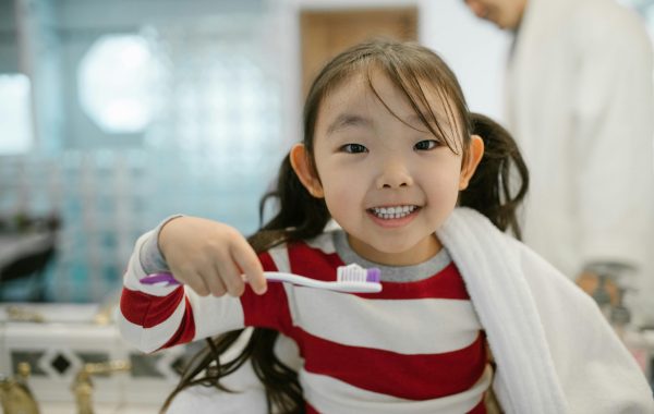 Young girl smiling and holding toothbrush